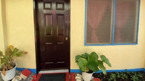 A brown door with a number 1 sign, a window with a blue frame, and two potted plants with green leaves. - Napo Beach Resort (Maripipi)