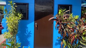 A blue building with a brown door, two windows, and a small porch area. - Napo Beach Resort (Maripipi)