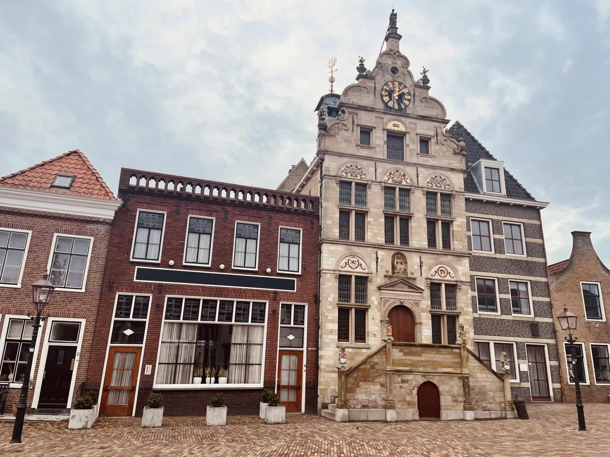A historic building with a prominent clock tower, a traditional facade, and a cobblestone street.