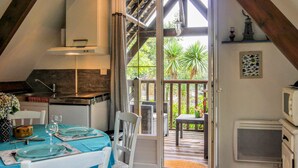 A cozy kitchen with a dining area, a view of the garden, and a small balcony.