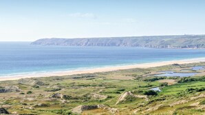 A coastal landscape with a beach, cliffs, and a river.