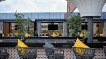 An outdoor seating area with wicker chairs and yellow cushions, a black countertop, and a patterned wall.