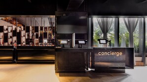 A modern reception desk with a 'concierge' sign, surrounded by shelves with various items and a large window with curtains. - Fiesta Americana Viaducto Aeropuerto (Mexico City)