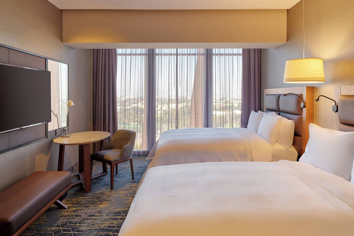 A hotel room with a large bed, a desk, a chair, and a TV.