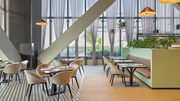 Un restaurante moderno con suelo de cuadros, ventanas amplias y una variedad de asientos, incluyendo mesas y una cabina.