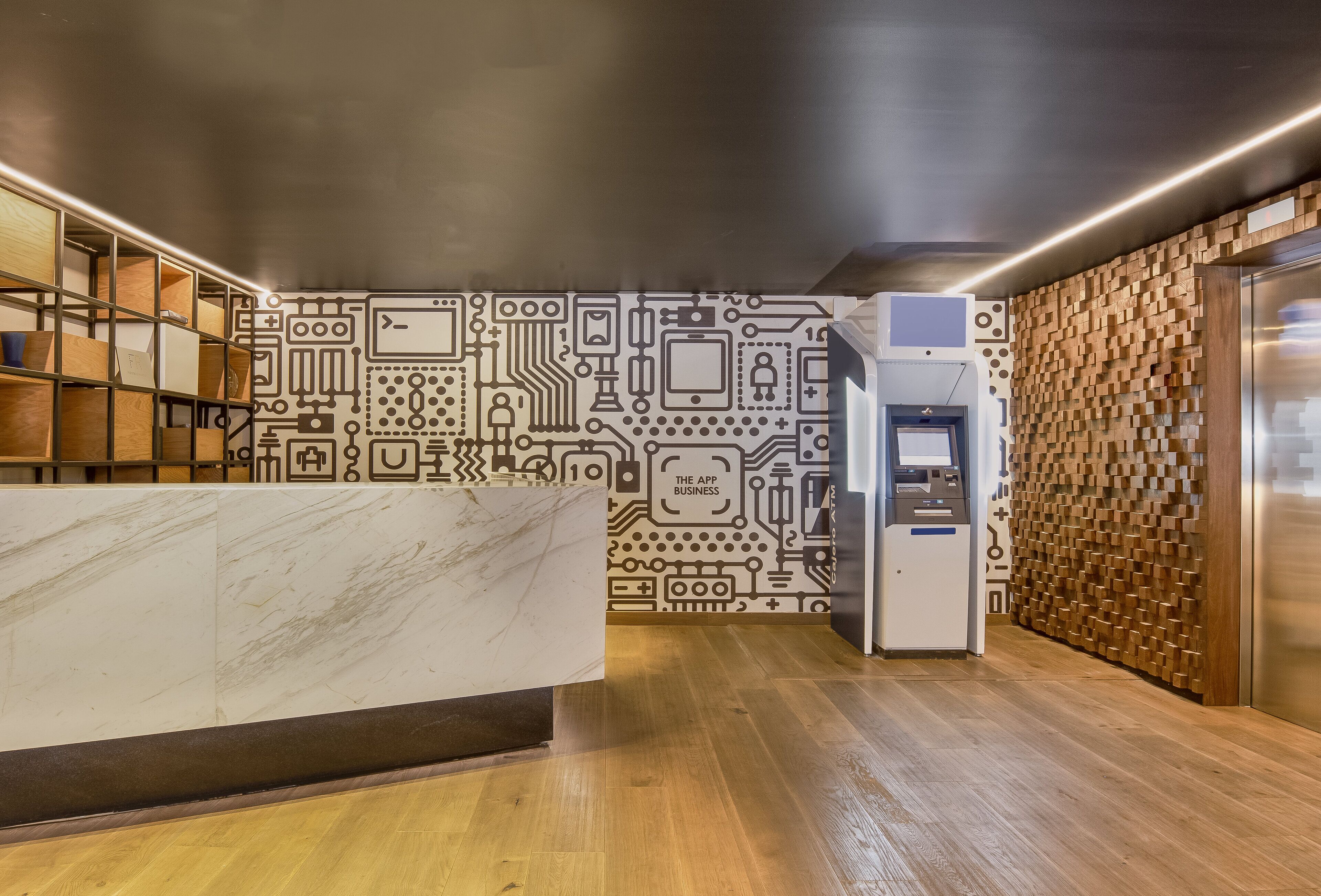 A modern reception area with a marble counter, a circuit board-themed wall, and a wooden wall with a textured pattern.