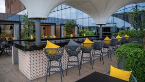 An outdoor bar area with a modern design, featuring a central bar with stools and a patterned wall. - Fiesta Americana Viaducto Aeropuerto (Mexico City)
