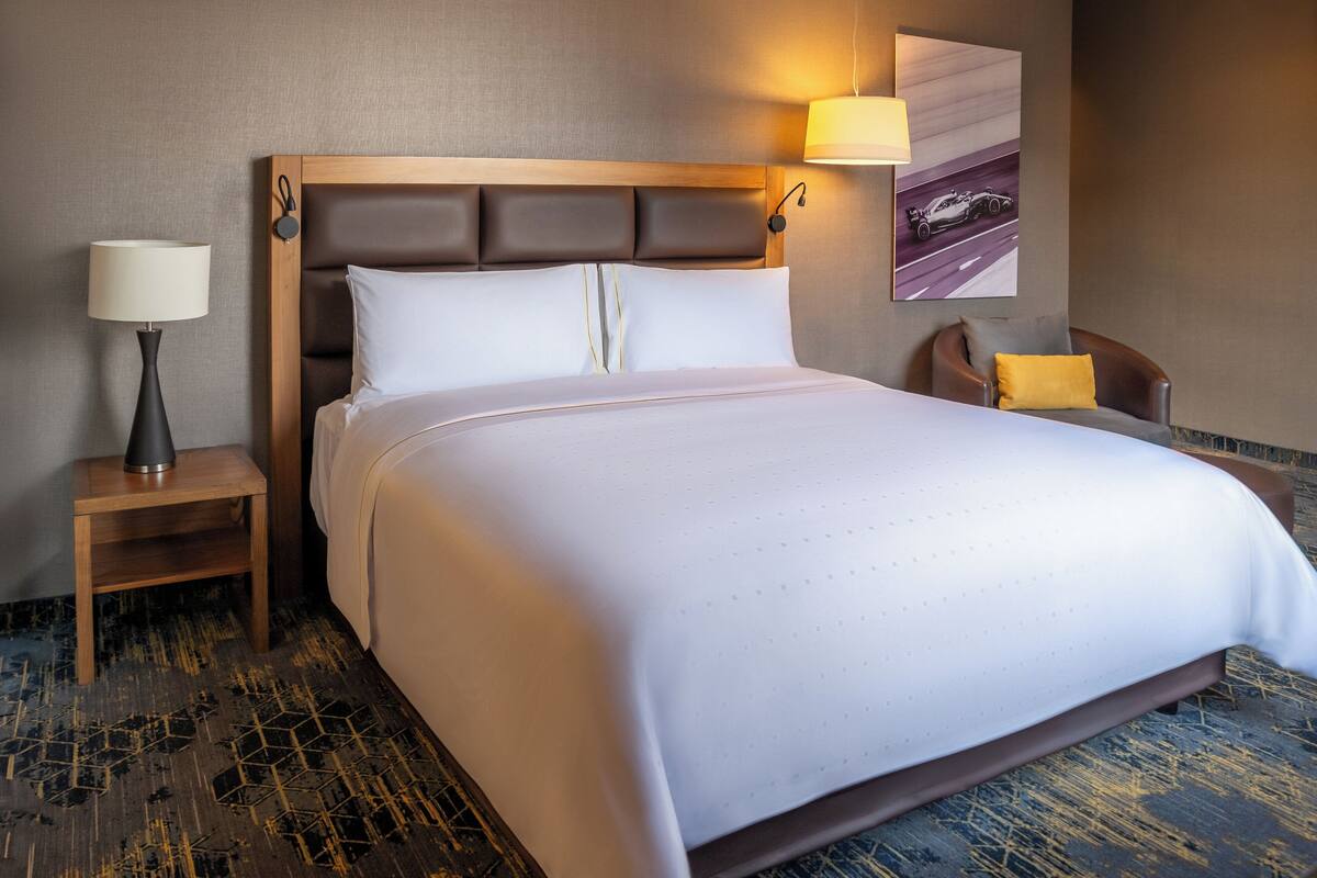 A neatly made bed with a wooden headboard, a bedside lamp, and a wall-mounted lamp.
