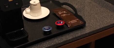 A coffee machine, a white cup, and a coffee pod on a countertop.