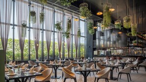 A restaurant with tables set for dining, large windows, and hanging plants. - Fiesta Americana Viaducto Aeropuerto (Mexico City)