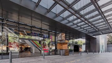 Un edificio moderno con fachada de vidrio, una escalera y un banco de madera.