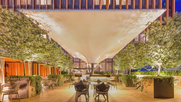 An outdoor dining area with tables and chairs, surrounded by greenery and a large canopy structure. - Fiesta Americana Viaducto Aeropuerto (Mexico City)