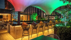 A modern bar area with a curved ceiling, seating, and a small indoor garden. - Fiesta Americana Viaducto Aeropuerto (Mexico City)