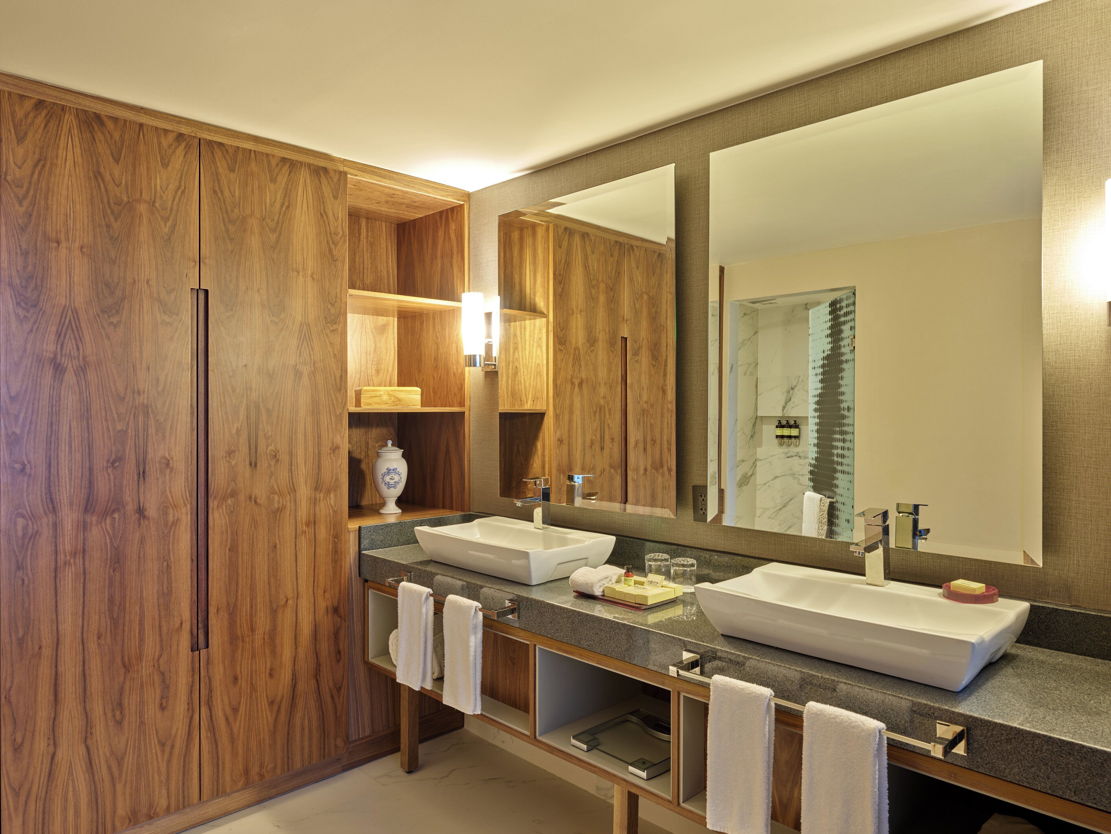 Un baño moderno con muebles de madera, un espejo grande y un tocador doble.