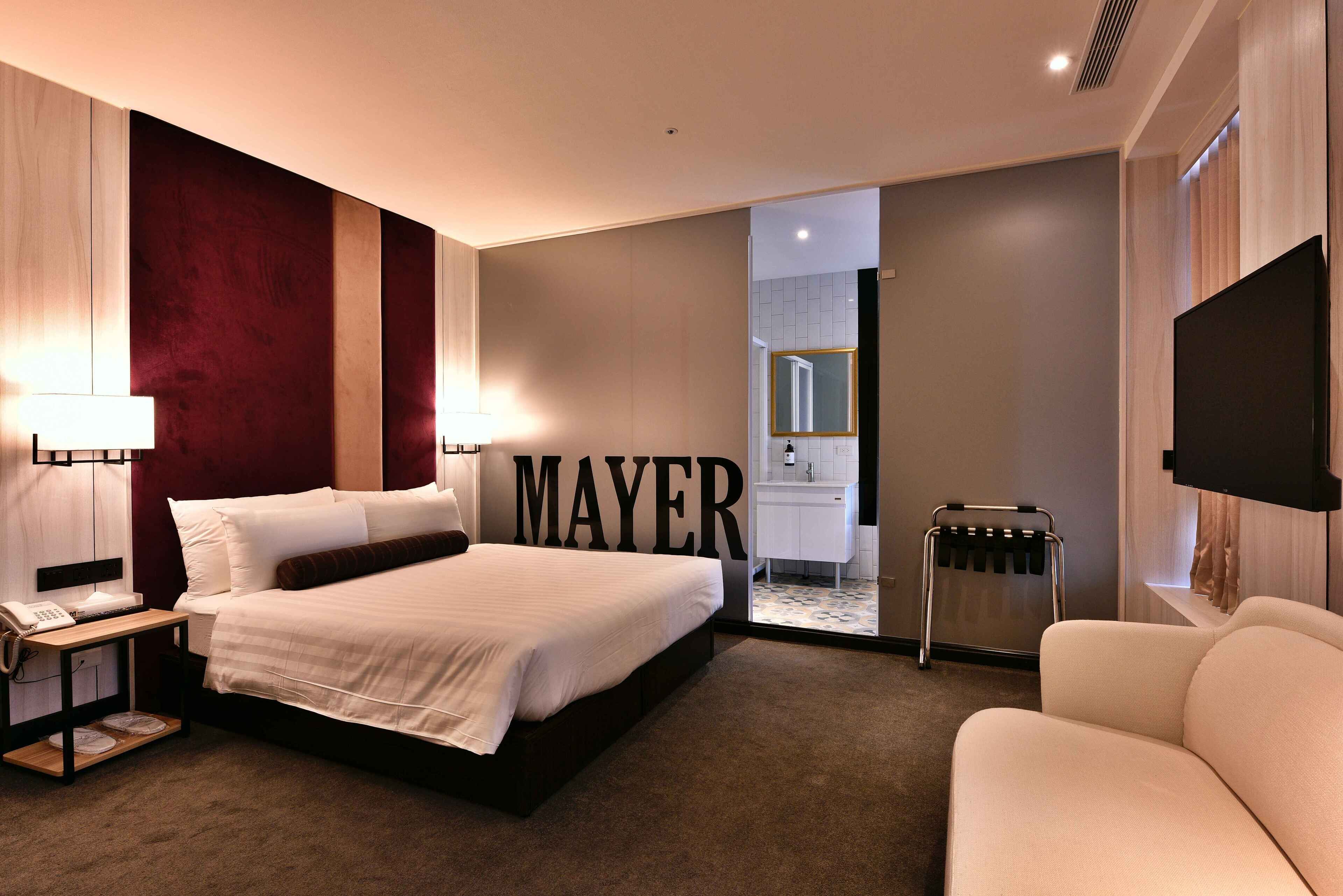 Een hotelkamer met een groot bed, een bureau met telefoon, een flatscreen televisie, een zithoek en een badkamer die door een geopende deur zichtbaar is.