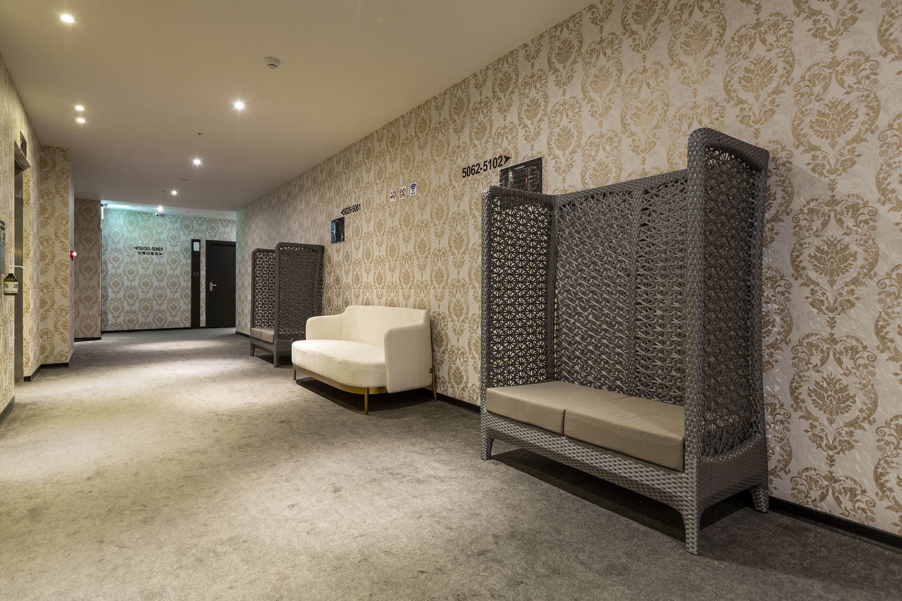 A hotel lobby with patterned wallpaper, a white sofa, and a decorative wall unit.