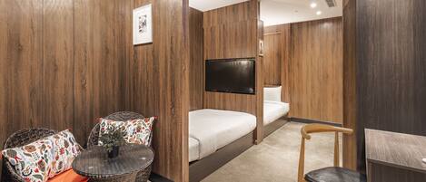 A modern room with a bed, a TV, wicker furniture, and a wooden wall panel.