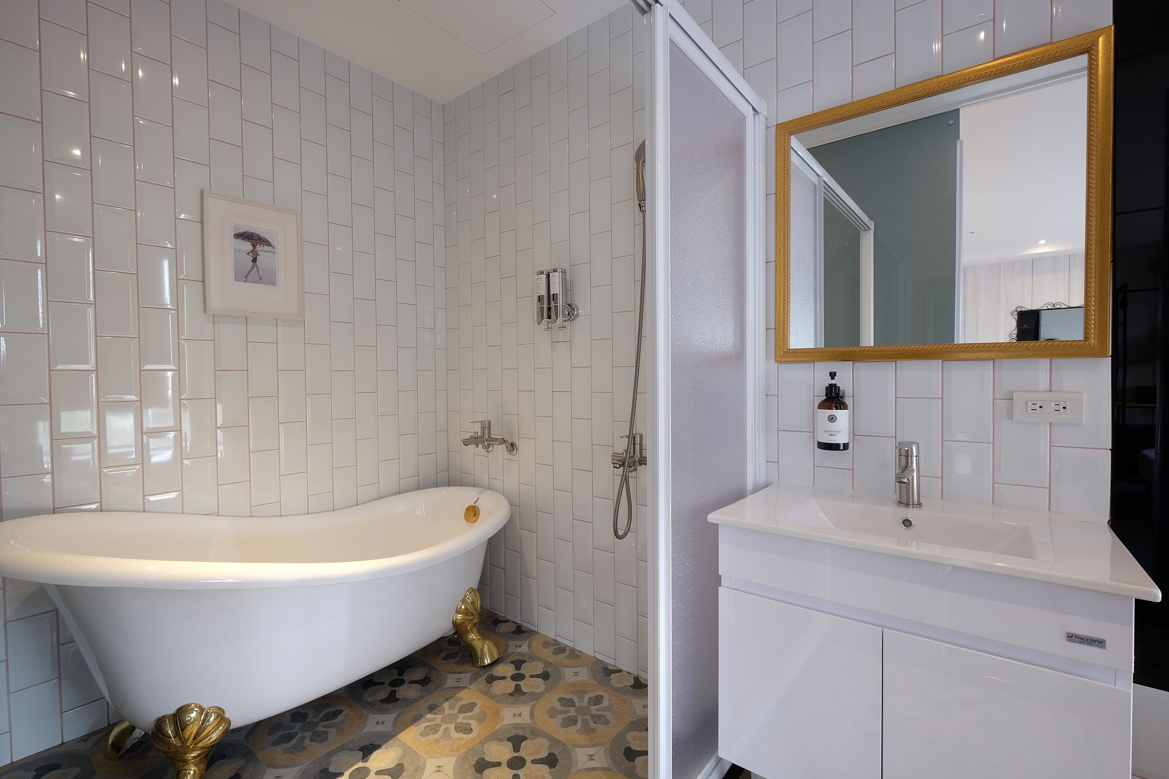 Un baño con una bañera independiente, ducha, lavamanos con espejo y suelo de baldosas.