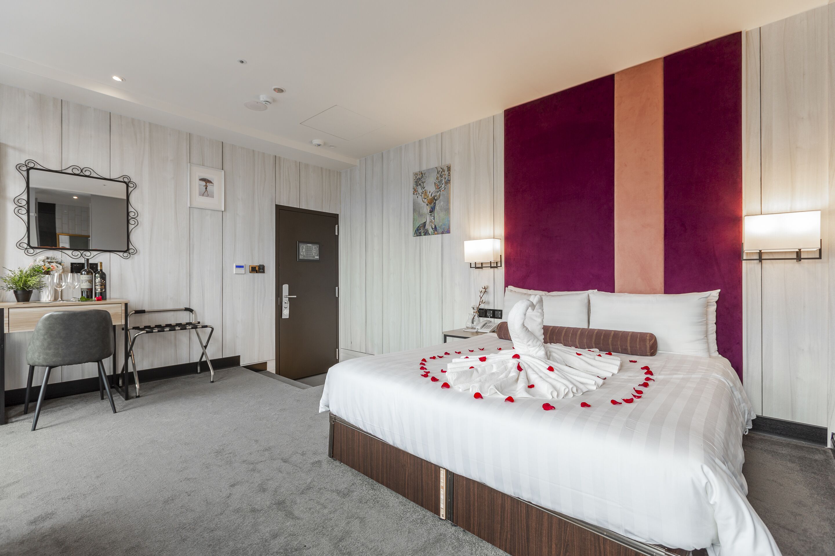 Une chambre d’hôtel avec un lit, un bureau, une chaise et un miroir.