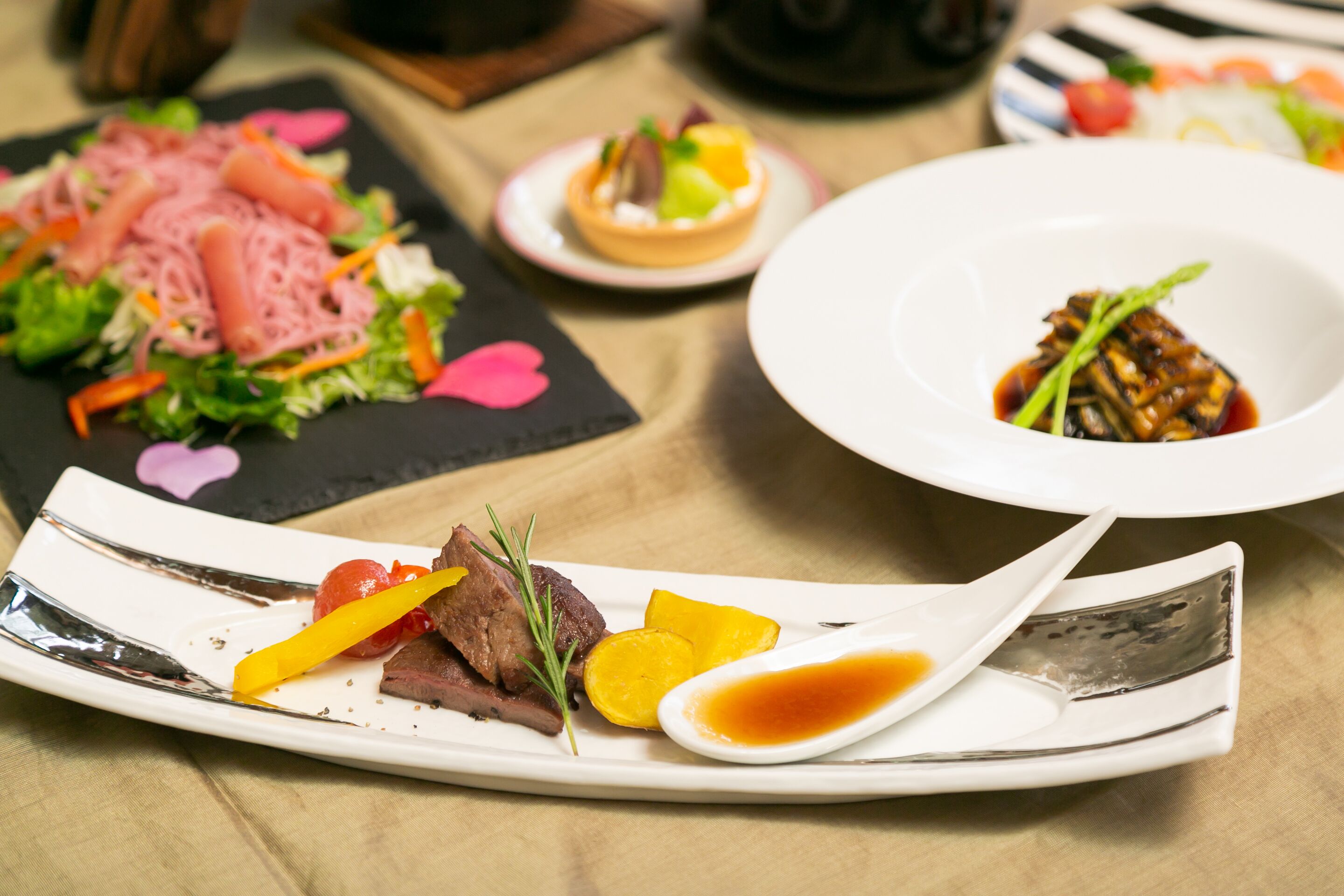 Variedad de platos sobre una mesa, incluyendo una ensalada, un guiso de carne y un postre.
