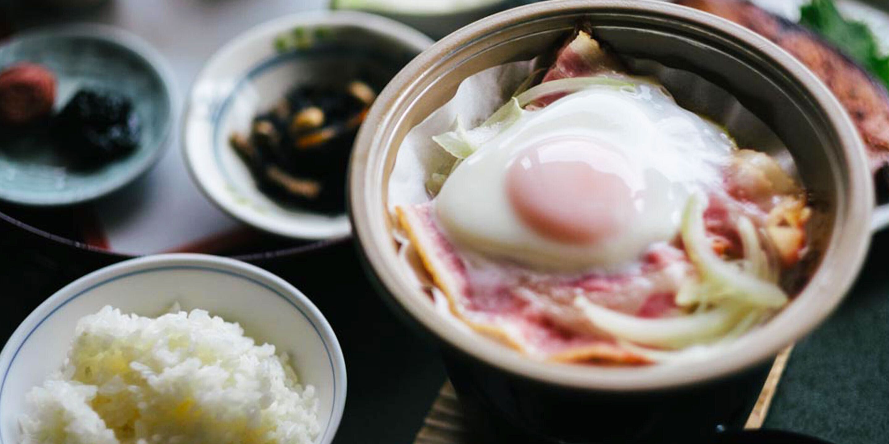 A bowl of food with a poached egg, rice, and vegetables.