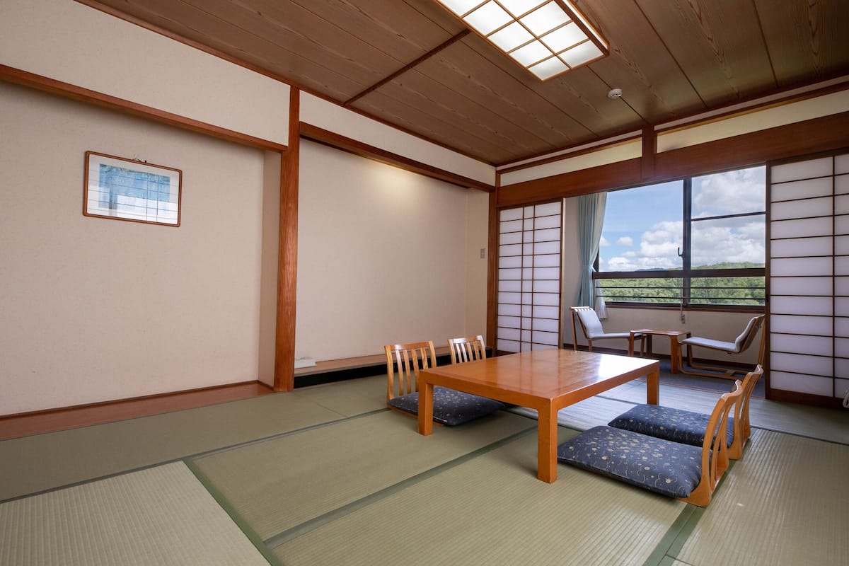Une pièce de style japonais traditionnel, avec un sol recouvert de tatamis, une table en bois et des chaises.