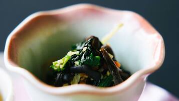 A bowl of food with greens and other ingredients.