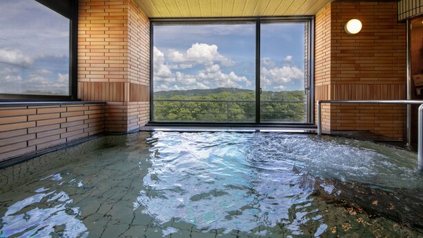 A hot tub area with a view of a mountainous landscape through large sliding doors. - Chikugofunagoya Kouennoyado (Chikugo)