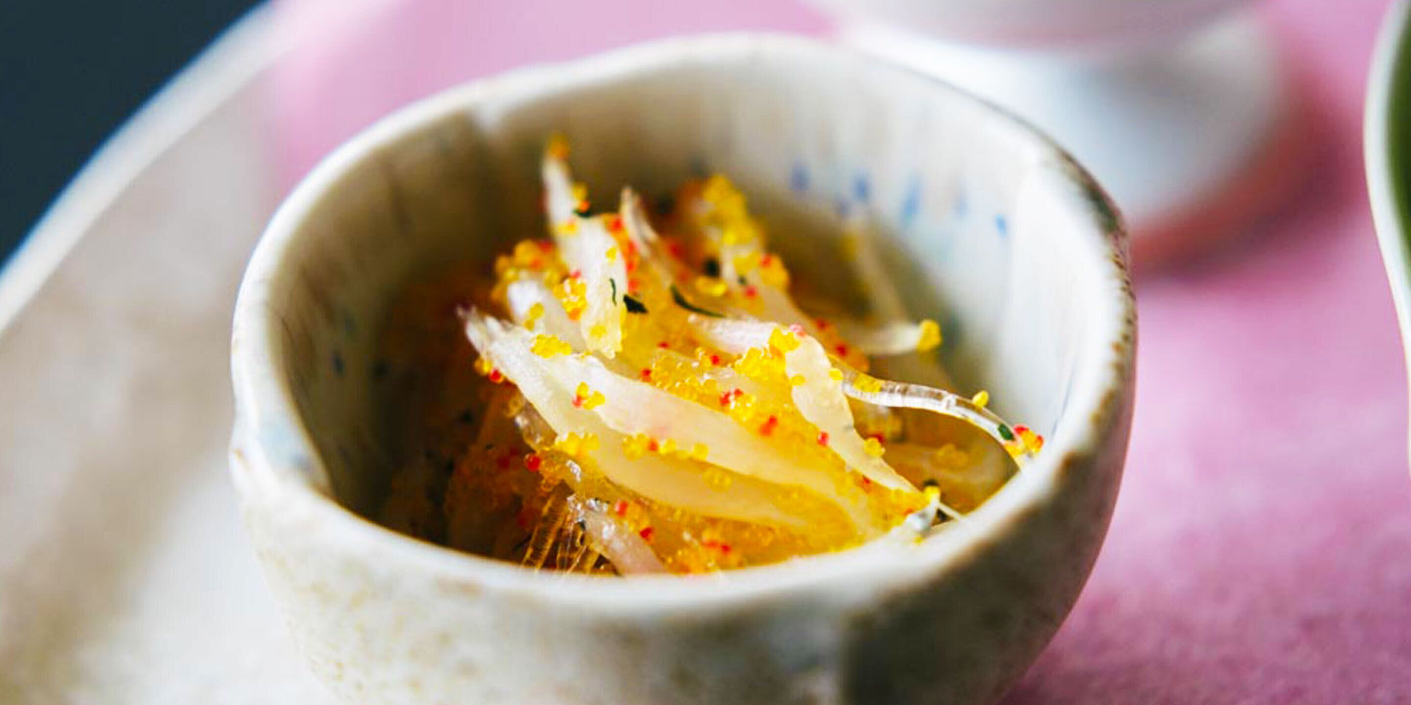 A bowl with a white interior and a pink background.