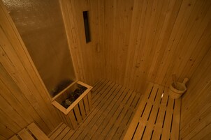 Una sauna de madera con techo inclinado, una ventana pequeña y un balde de madera.