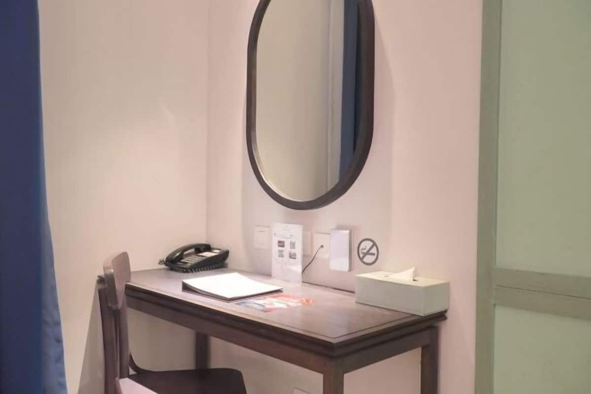 A hotel room with a desk, a telephone, a tissue box, and a wall-mounted mirror.
