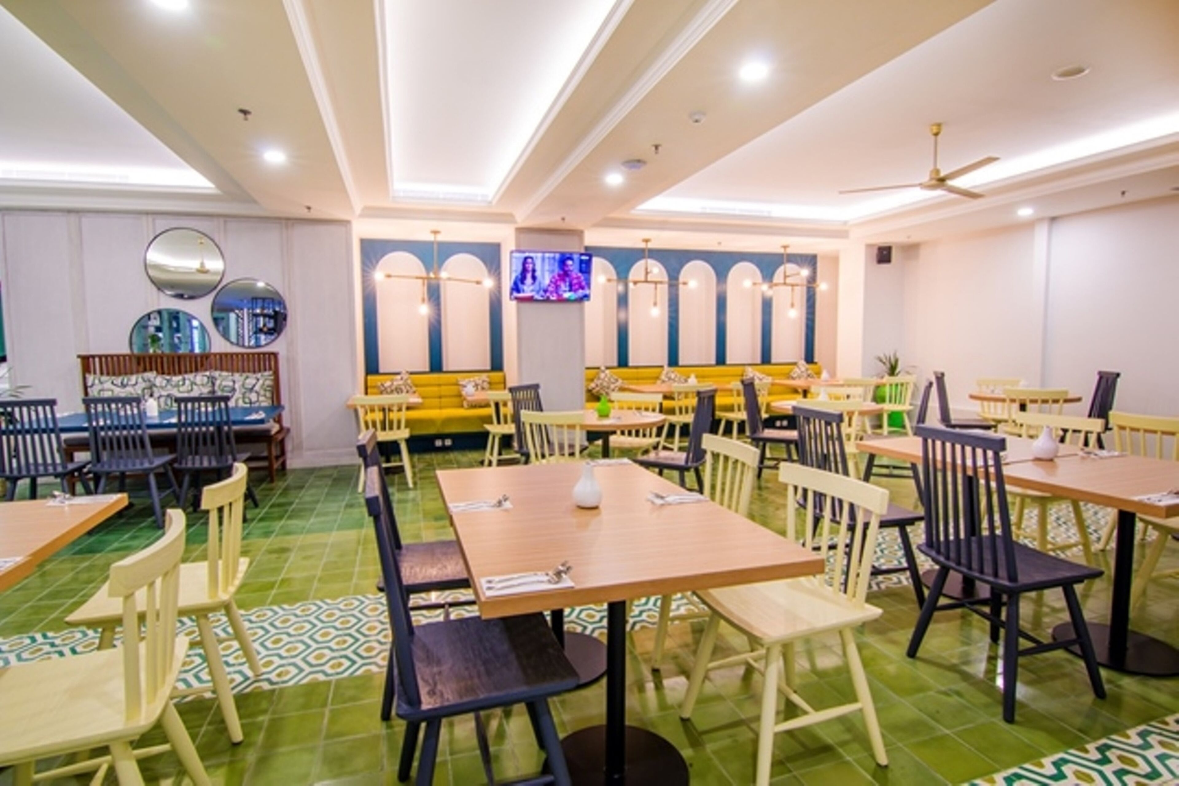 Un restaurante con varias mesas y sillas, una pantalla de televisión y un ventilador de techo.