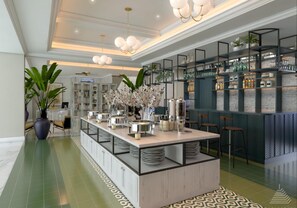 A modern kitchen with a central island, bar area with shelves, and a seating area with chairs. - Jambuluwuk Thamrin Hotel (Jakarta)