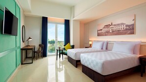 A hotel room with two beds, a desk, a chair, a TV, and a balcony with a view. - Jambuluwuk Thamrin Hotel (Jakarta)