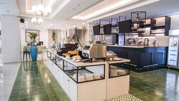 Un hall d’hôtel moderne comprenant un comptoir d’accueil, un espace buffet et un bar.