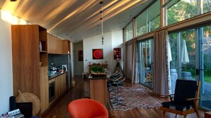 A modern kitchen with wooden cabinets, a central island, and a dining area with a red chair and a black chair.