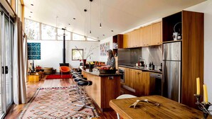 A modern kitchen with wooden cabinets, stainless steel appliances, and a bar area with stools.