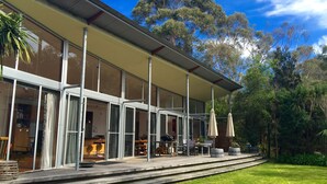 A modern house with large glass windows, a covered patio, and a well-maintained lawn.