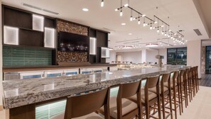 A modern kitchen with a long island, bar stools, and built-in appliances. - Courtyard by Marriott Thousand Oaks Agoura Hills (Agoura Hills)
