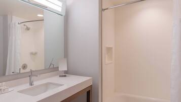 A modern bathroom with a large mirror, two sinks, a shower, and a towel rack.