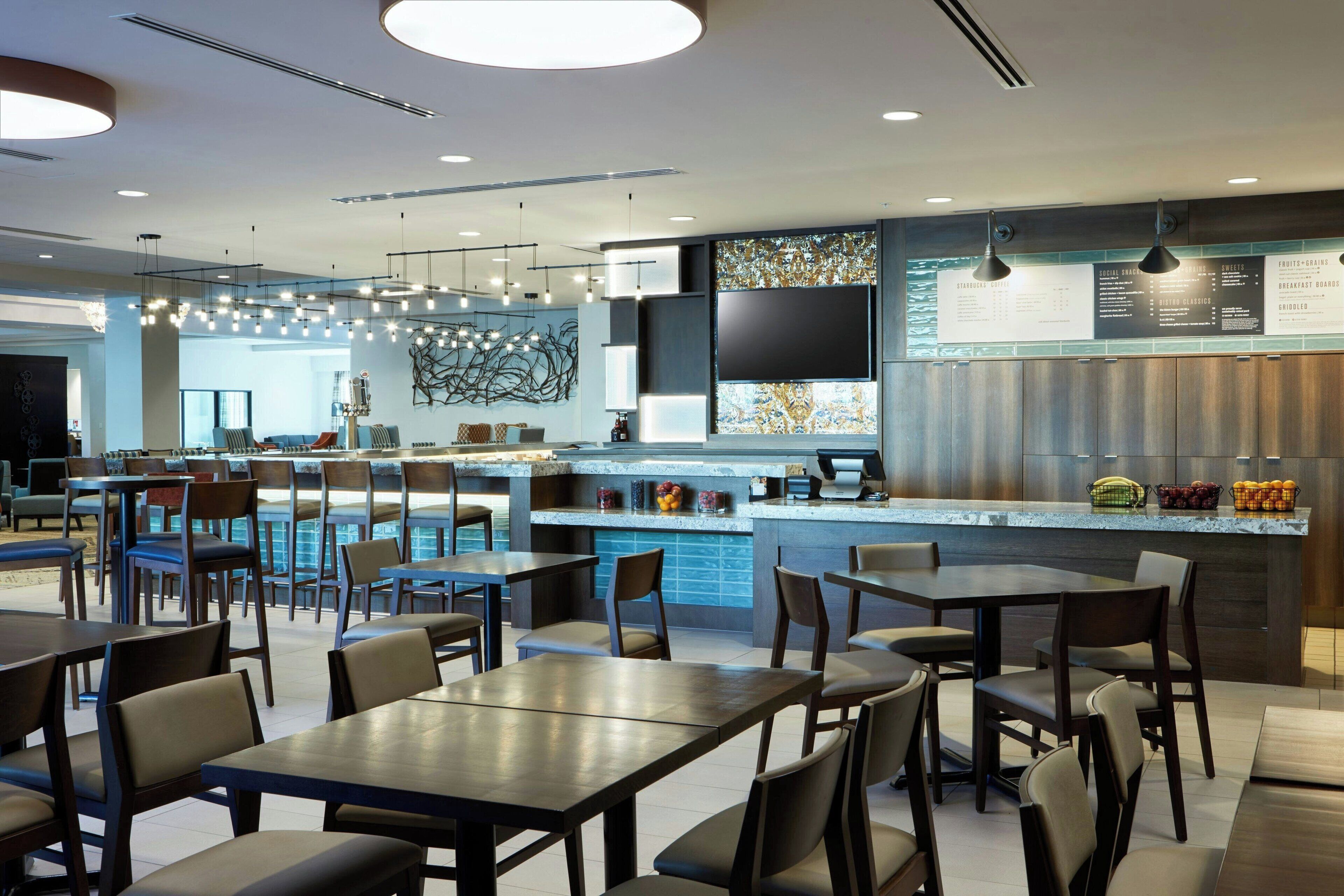 A modern restaurant with a bar area, seating arrangements, and a menu board.
