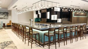 A modern bar area with a long counter, multiple bar stools, and a contemporary light fixture. - Courtyard by Marriott Thousand Oaks Agoura Hills (Agoura Hills)