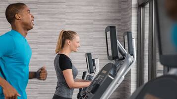 A gym with treadmills and a person running.