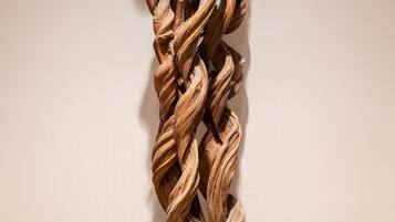 A wooden sculpture on a black base against a plain wall.