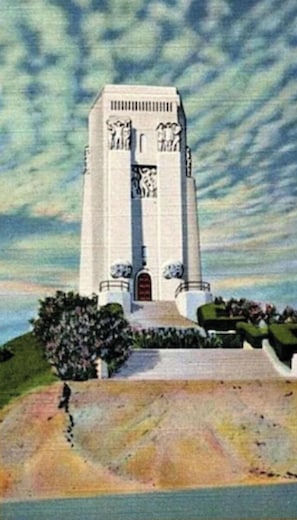 A tall, white building with a central entrance and steps leading up to it.