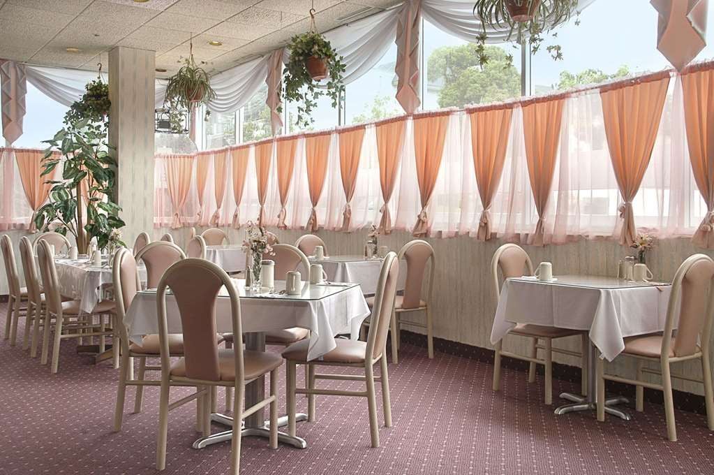 A dining area with round tables, chairs, and draped curtains.