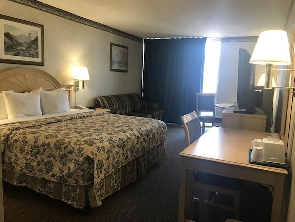 Habitació d'hotel amb un llit, un sofà, una taula de treball i una cadira.