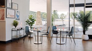 A modern interior with a dining area, large windows, and artwork on the walls. - Glendale Express Hotel (Glendale)
