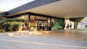 A modern building with a large glass entrance, outdoor seating, and potted plants. - Glendale Express Hotel (Glendale)