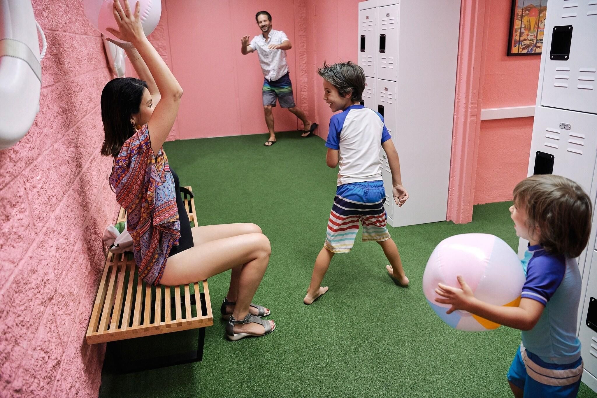 A room with artificial turf, lockers, and a bench.